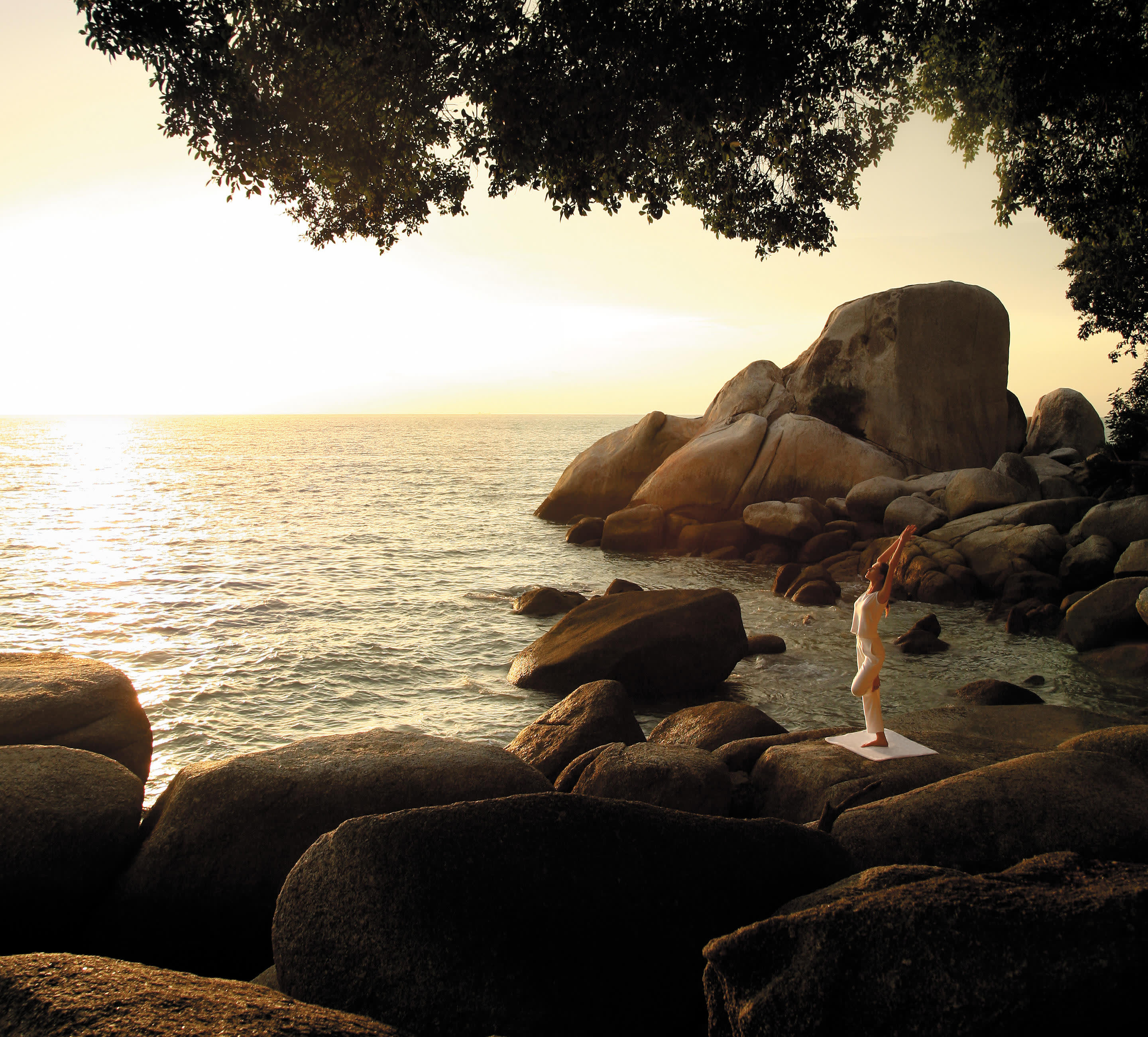 a group of people sitting on a rock next to a body of water