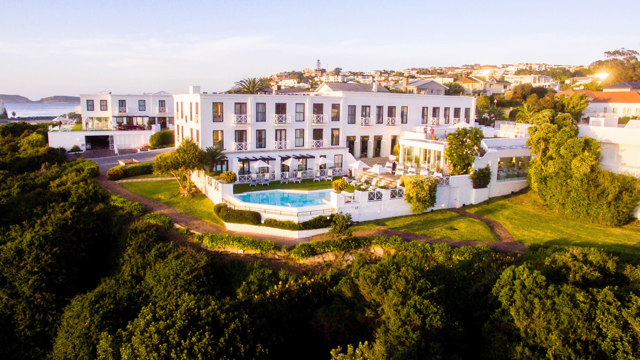 a large white building with grass and trees