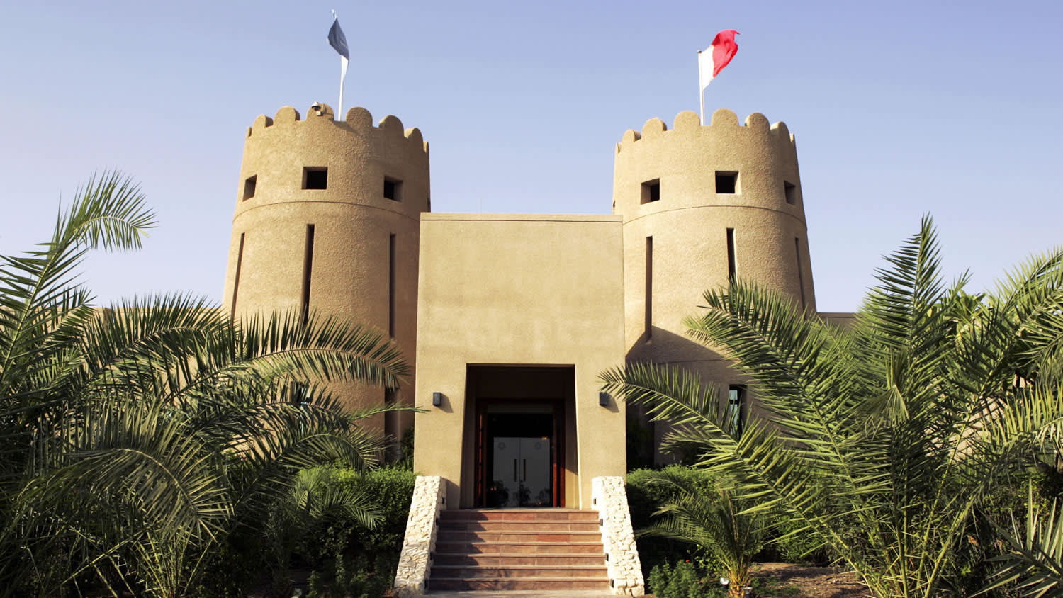 a clock tower in front of a palm tree