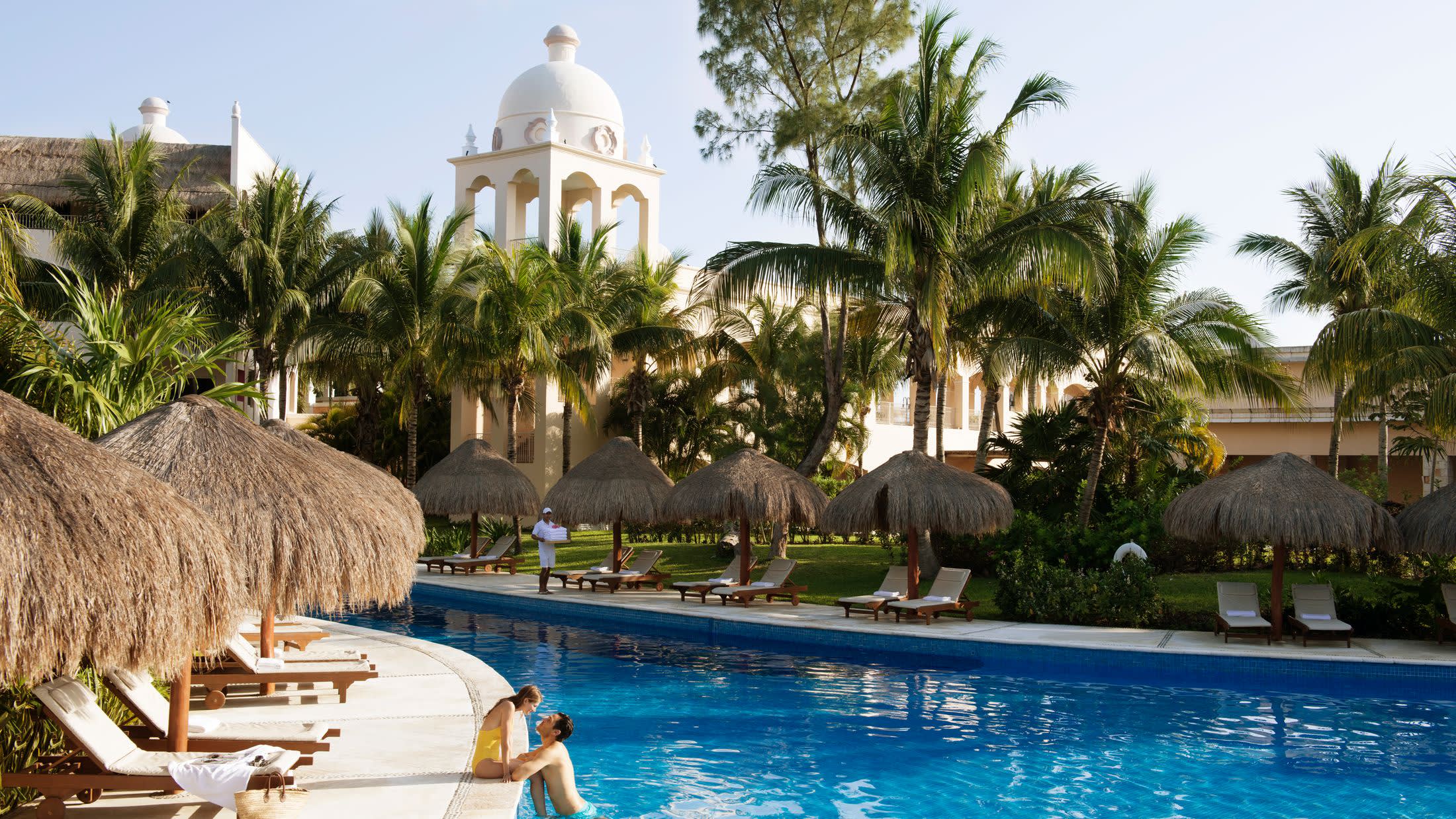 a group of palm trees next to a pool of water