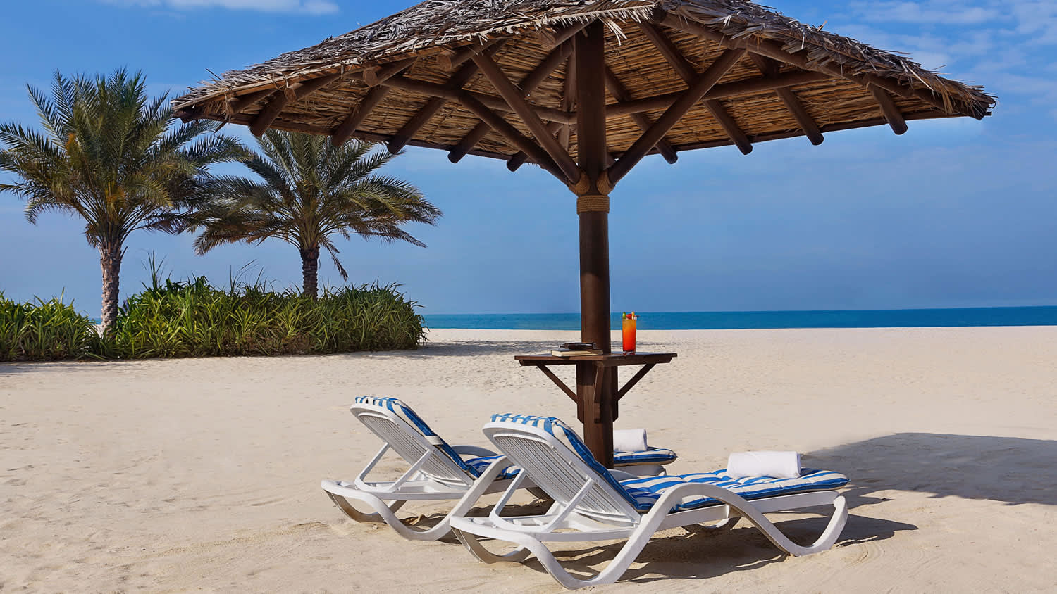 a couple of lawn chairs sitting on top of a sandy beach