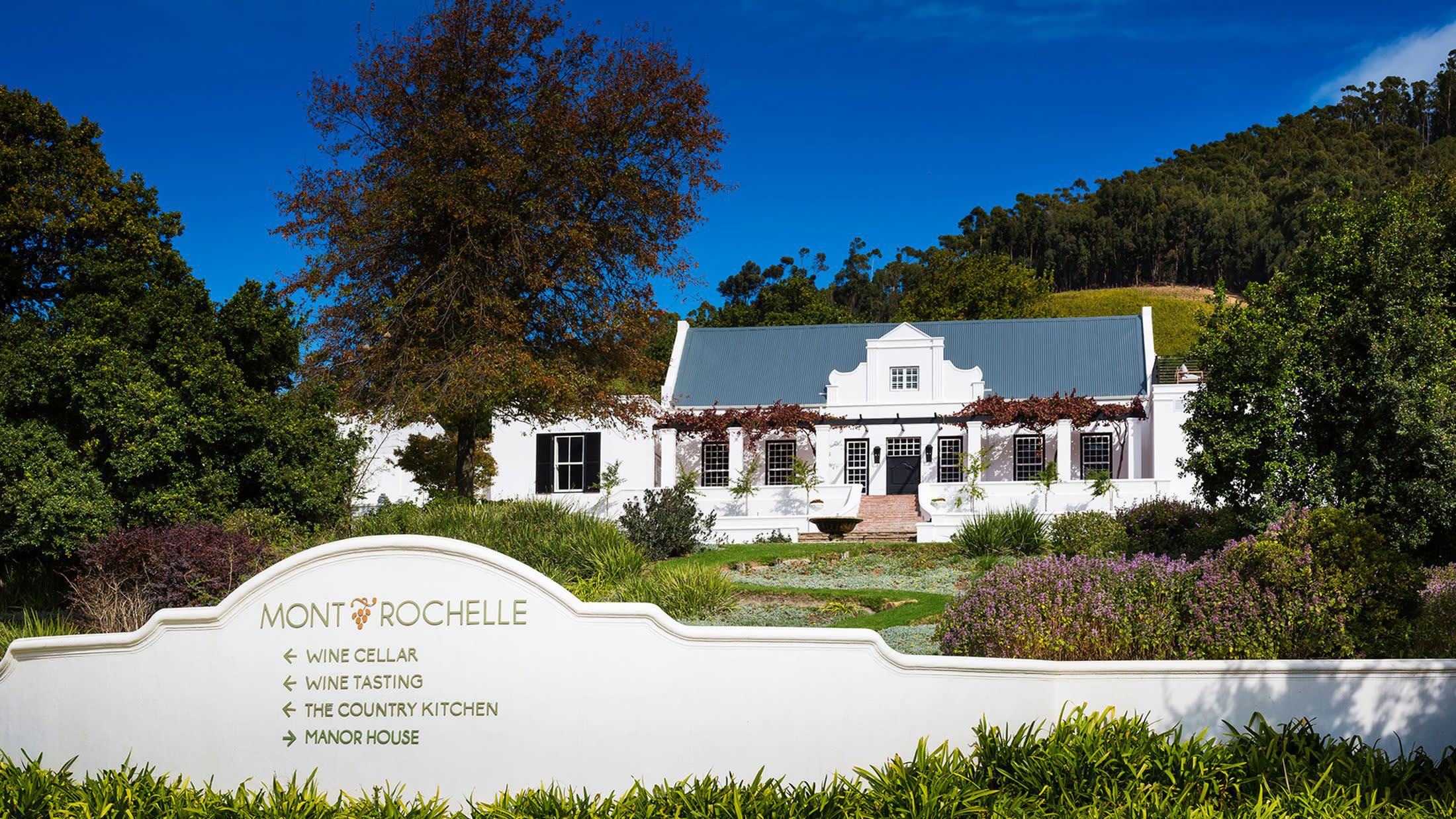a large white house with bushes in the background