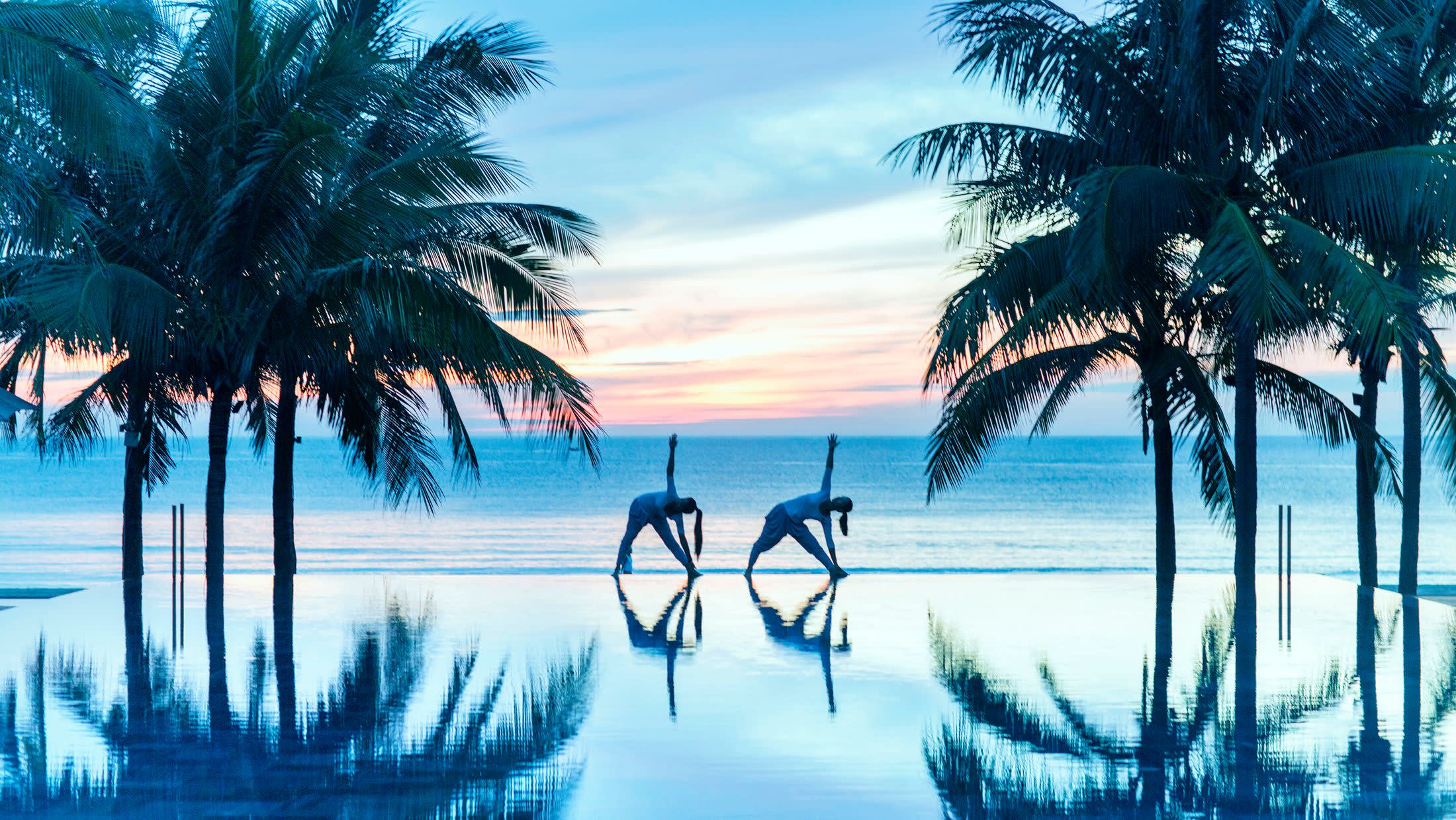 a group of palm trees next to a body of water
