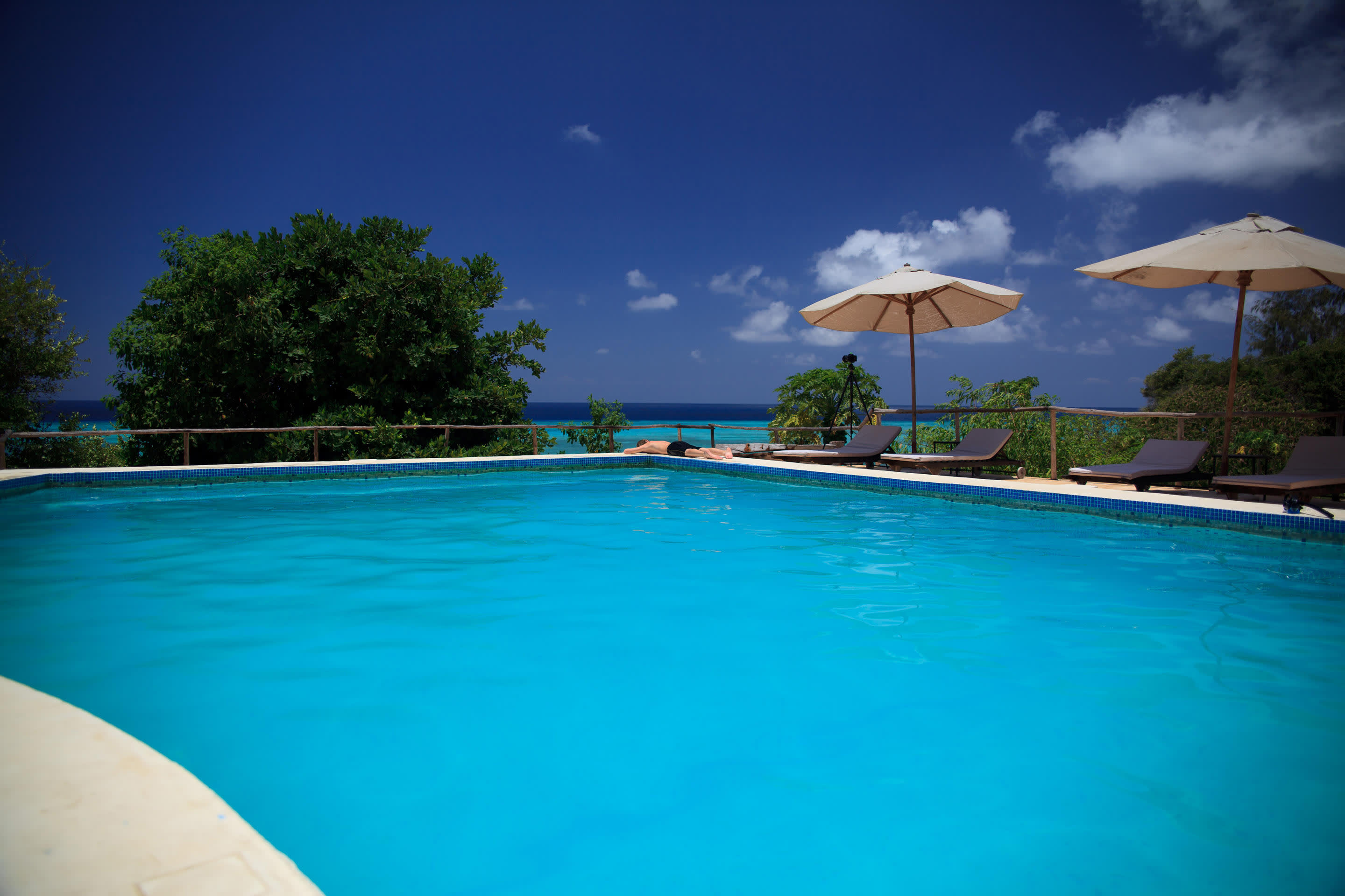 a group of lawn chairs sitting on top of a blue pool of water