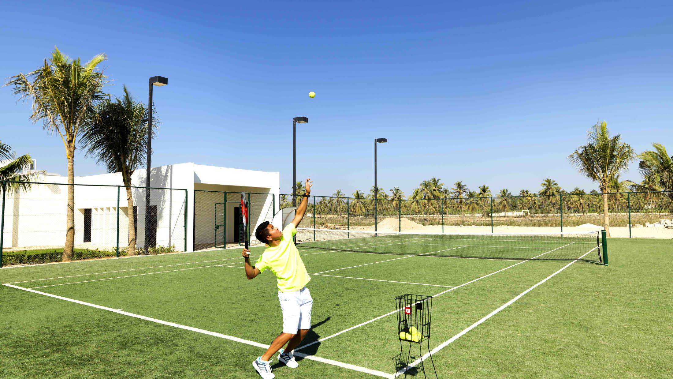 a man holding a football ball on a court with a racket