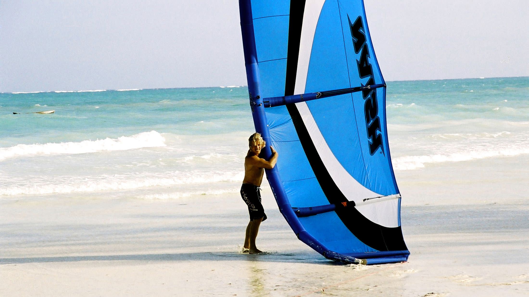 a person standing on a beach holding a surf board