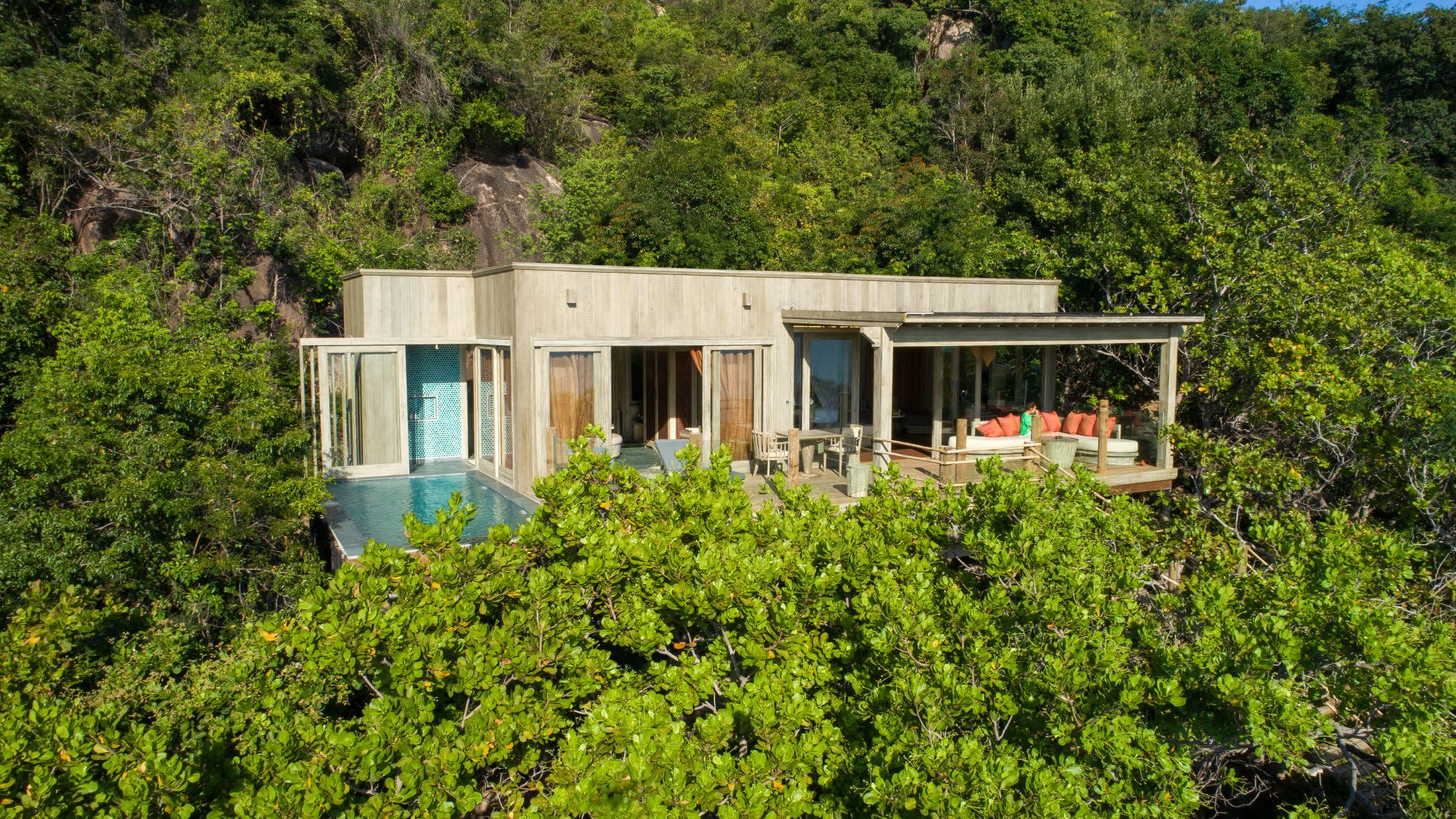 a house with bushes in front of a tree