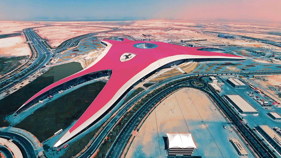 a train is parked on the beach with Ferrari World Abu Dhabi in the background