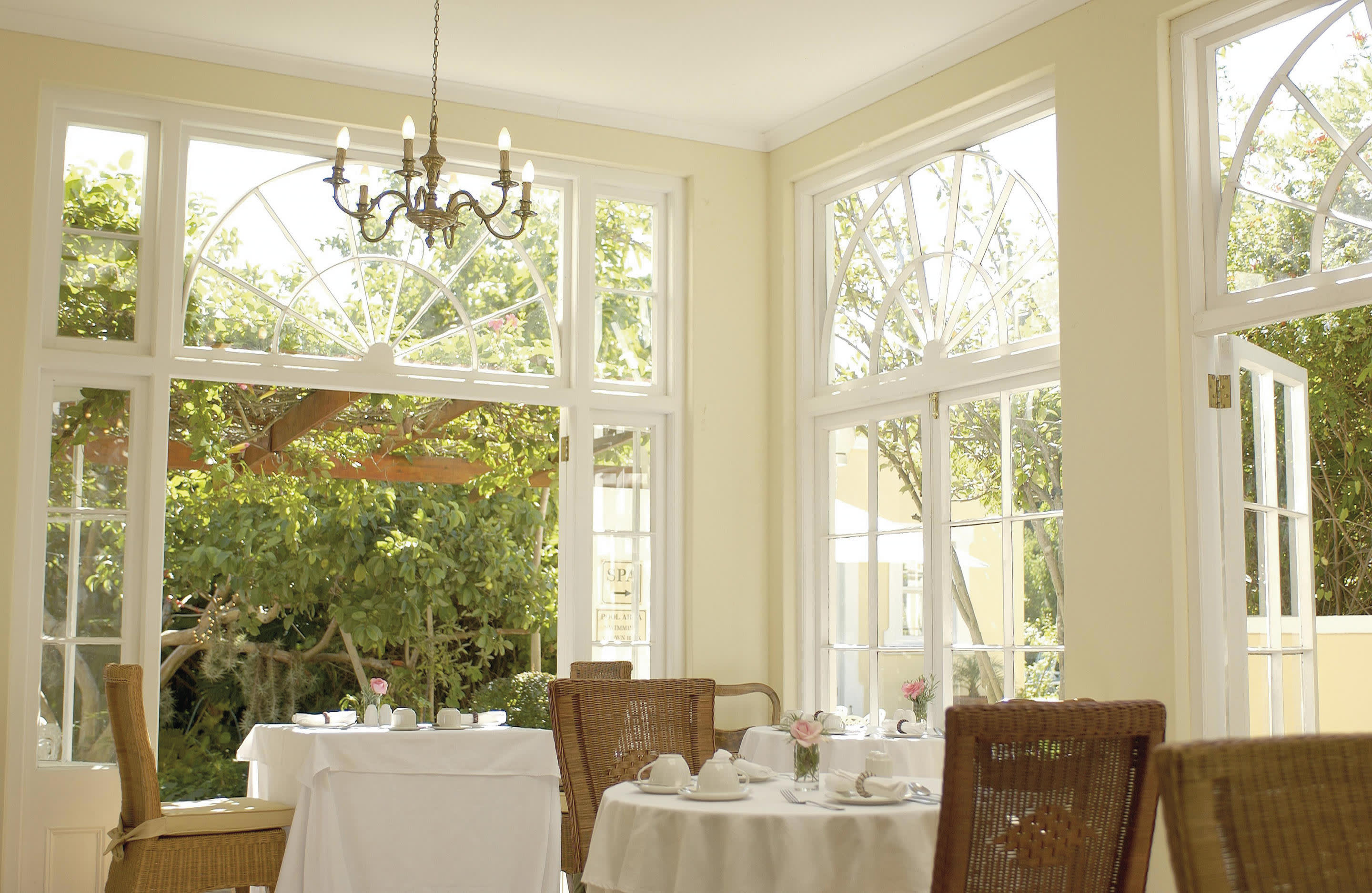 a room filled with furniture and vase of flowers on a sunny window