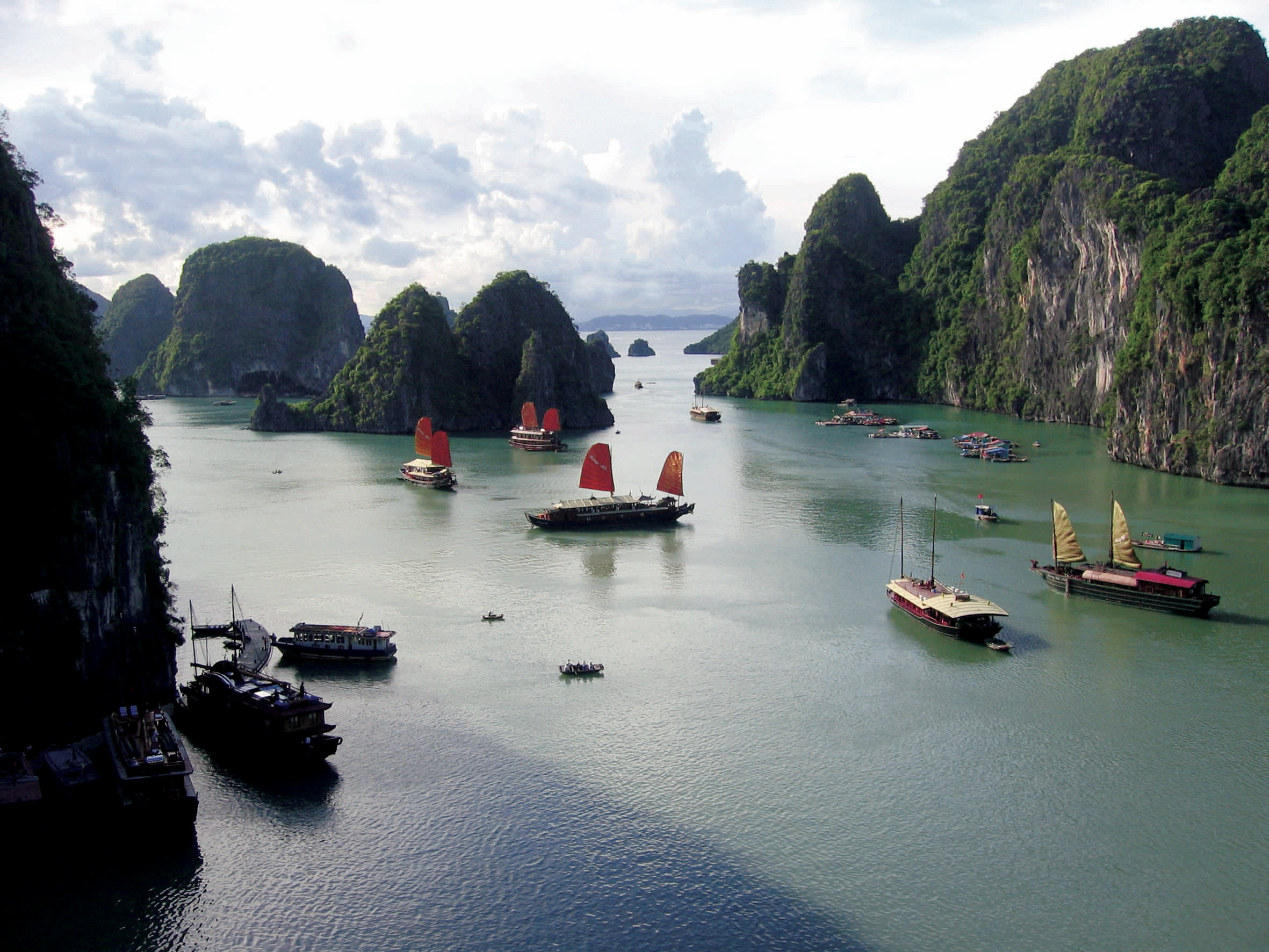 a group of people in a small boat in a body of water with Ha Long Bay in the background