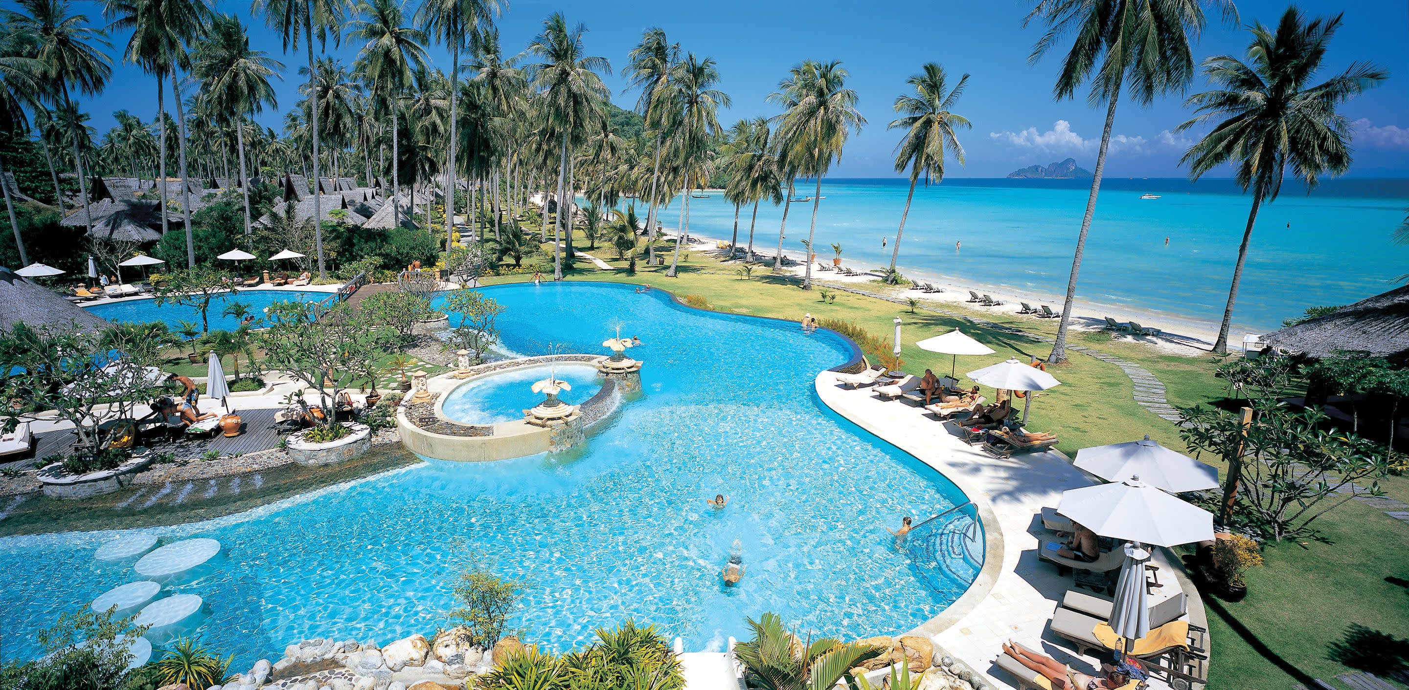 a pool next to a body of water surrounded by palm trees