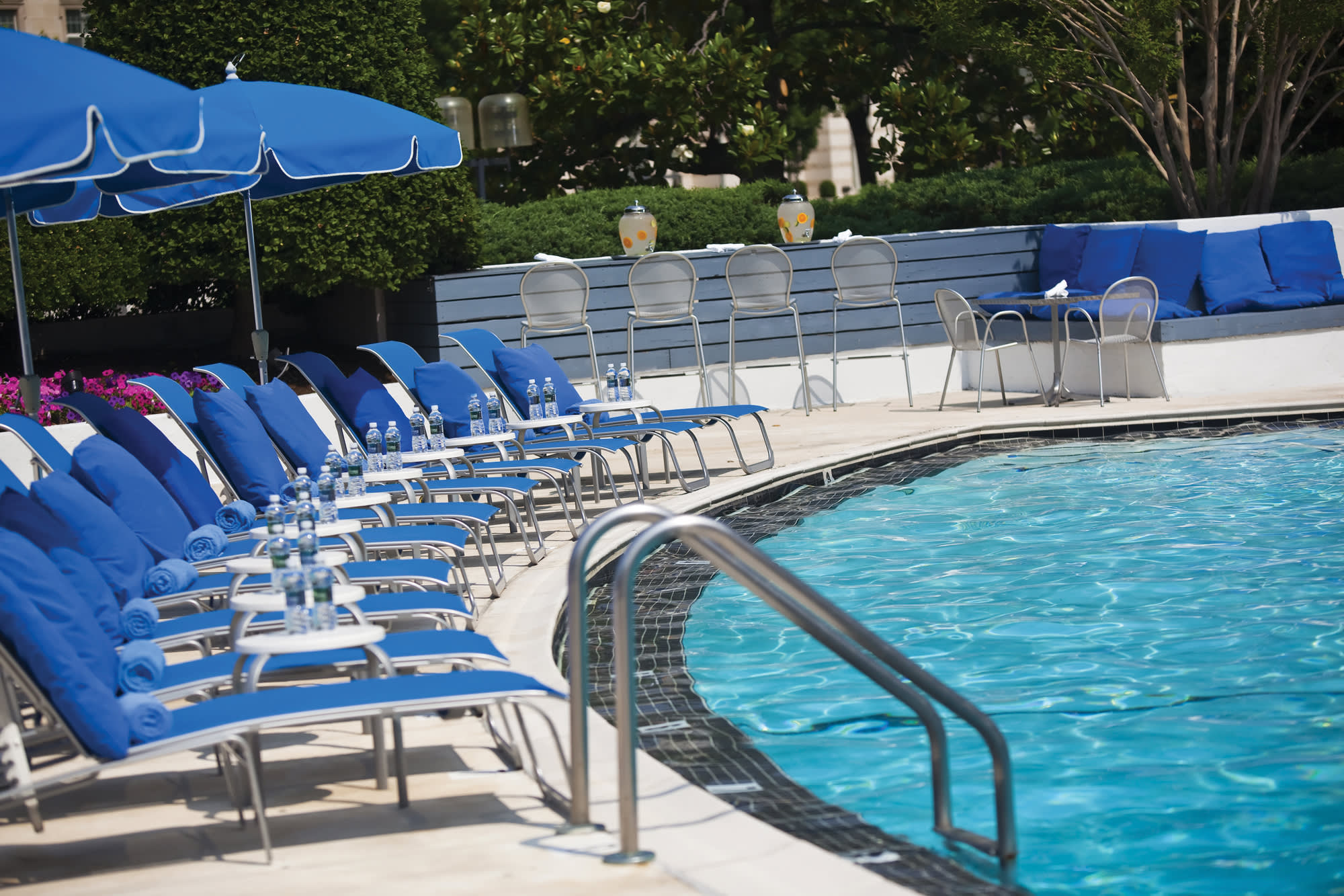 a row of lawn chairs sitting next to a pool of water