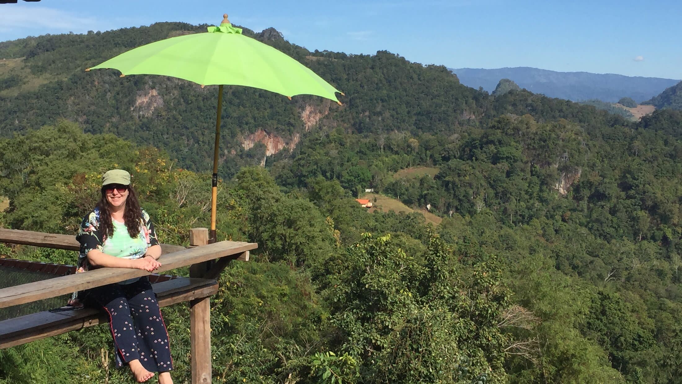 a person sitting on a bench with a mountain in the background