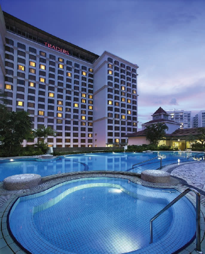 a pool next to a body of water with a city in the background