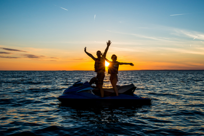 Couple jetskiing while sun sets