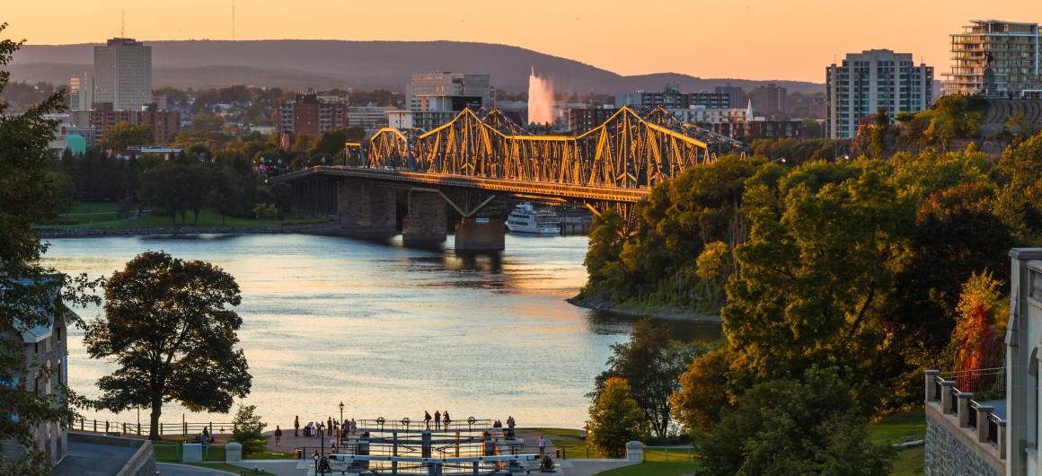 Golden sunset light hits the Alexandra Bridge in Ottawa as it spans the Ottawa River near the entrance of the Rideau Canal.