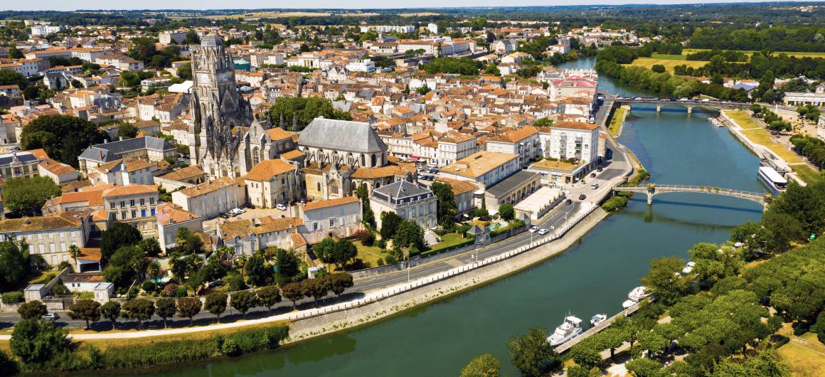 Luchtfoto van Saintes met de romaanse kathedraal en rood betegelde daken aan beide zijden van de rivier de Charente.