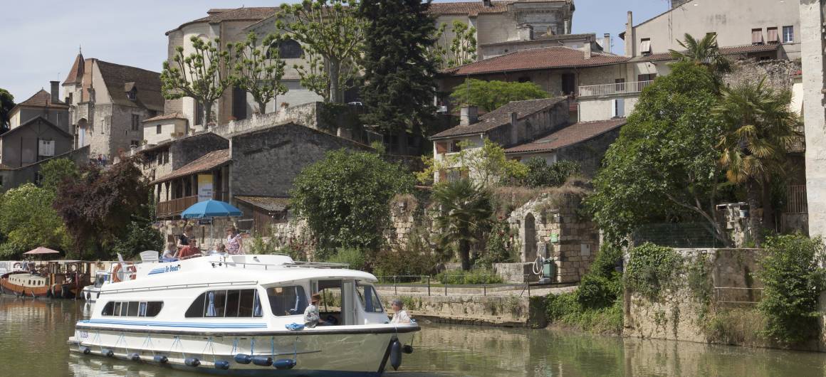 Un bateau navigue à travers un village pittoresque en Aquitaine.