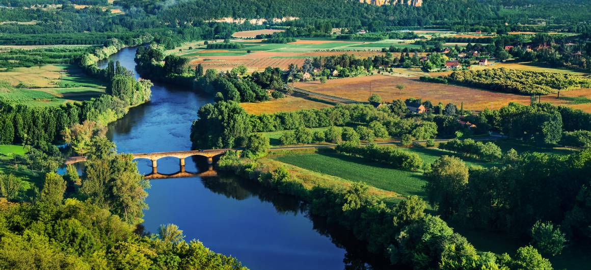Un pont fluvial paisible s'étend à travers une vallée verdoyante en Aquitaine.