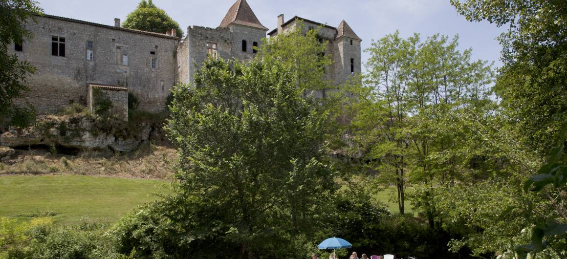 Un bateau passe devant un château historique en bord de rivière en Aquitaine.