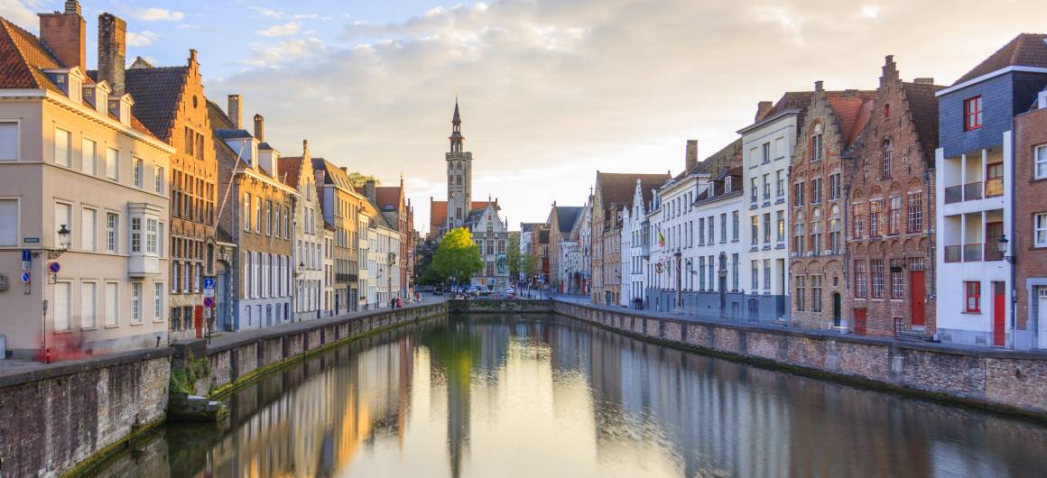 Still waters reflecting historic houses along Bruges' canal, charming moments in Belgian heritage towns.