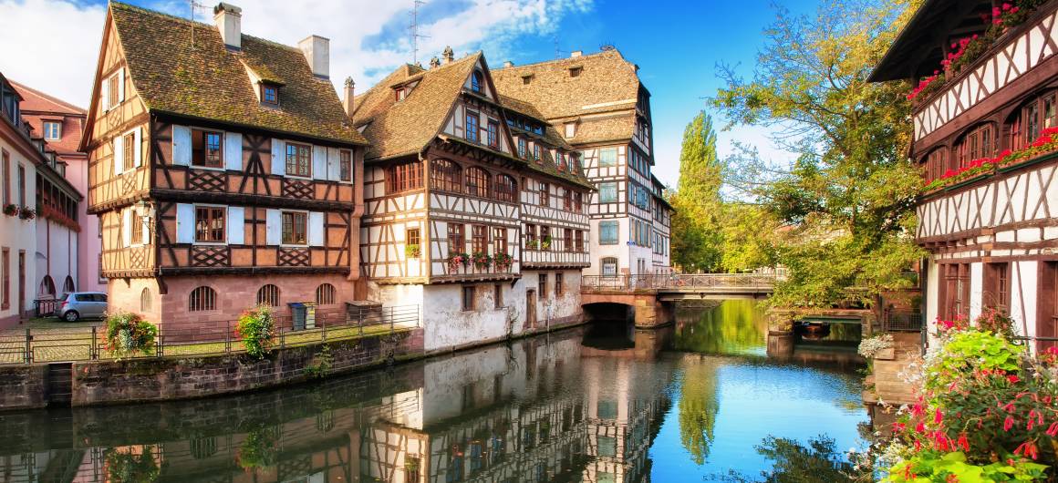 Maisons traditionnelles à colombages se reflétant dans les eaux calmes du canal, dans le quartier historique de la Petite France à Strasbourg.
