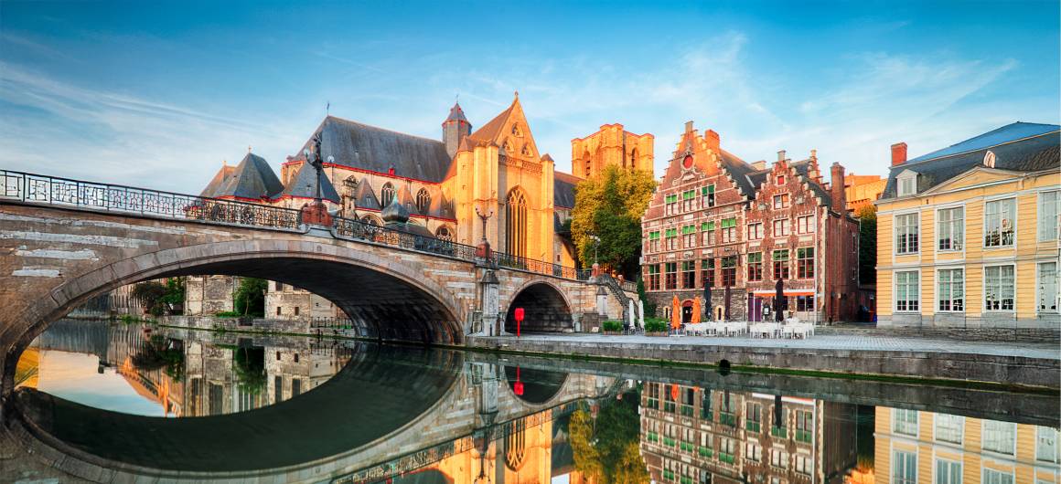 Peaceful morning view of Ghent canal with historic buildings, discover Flemish charm in Belgium.