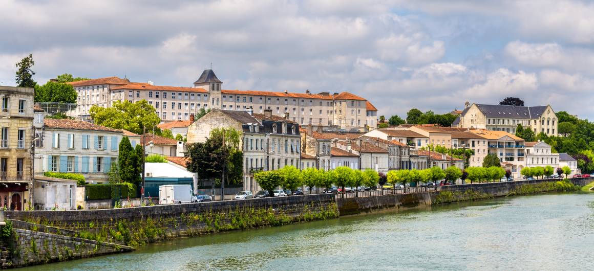 Historische gebouwen aan het water in de stad Cognac, met met bomen omzoomde straten en de Charente die eronder stroomt.