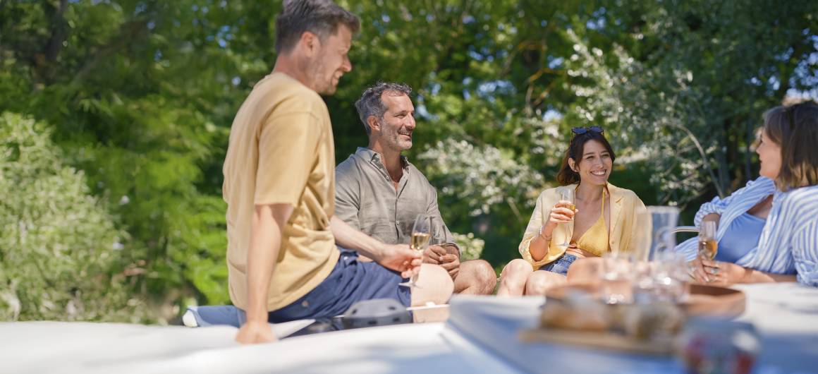 Friends sharing drinks and laughter on the boat, enjoying each other's company under sunny skies.