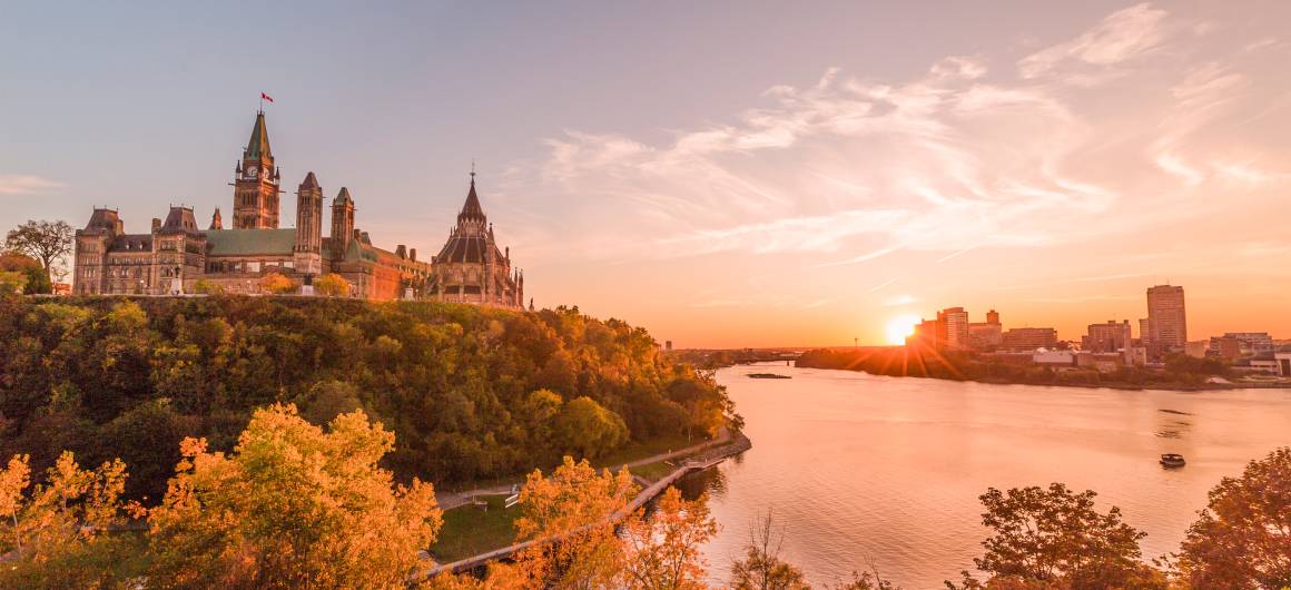 The Rideau Canal locks run through the heart of Ottawa with Parliament Hill and Château Laurier glowing under a soft evening sky.