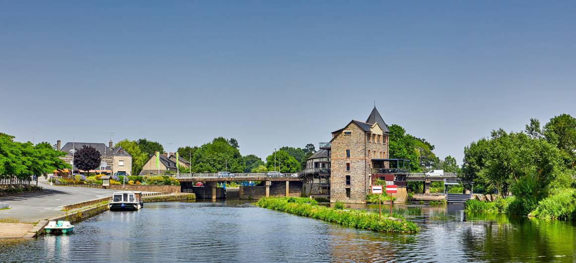 Picturesque view of Messac with a river weir and traditional town buildings lining the waterfront.