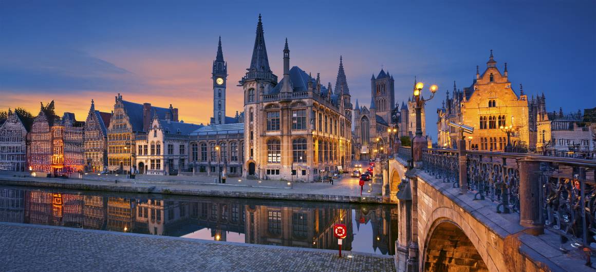 Night-time view of Ghent's waterfront illuminated by city lights, experience romantic evenings in Flanders, Belgium.