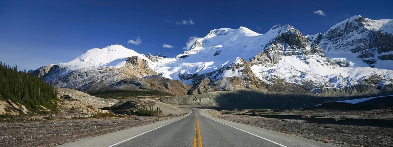 a snow covered road with a mountain in the background