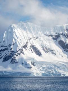 A snow covered mountain emerging from the Antarctic ocean