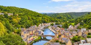 Historic town of Dinan nestled along the river, with stone buildings, surrounding hills, and natural greenery.
