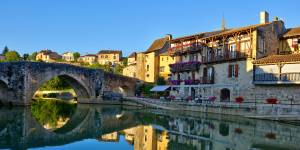 Terrazze dei caffè con vista sul fiume accanto a un ponte storico in Aquitania.