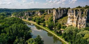 Ein Boot fährt auf einem Fluss unter dramatischen Kalksteinfelsen in Merry-sur-Yonne, Burgund.