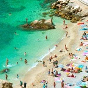 Enchanting Travels France Tours beach of the Cote d'Azur with tourists with sunbeds and umbrellas on the hot summer day