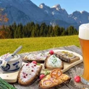 Hearty snack with different kinds of spreads on farmhouse bread served with a fresh yeast wheat beer on an old wooden table in the Bavarian Alps