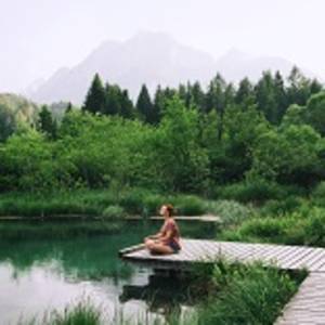 Young woman doing yoga and meditating in lotus position on the background of nature. Concept of Meditation, Relaxation and Healthy Life. Slovenia, Europe.