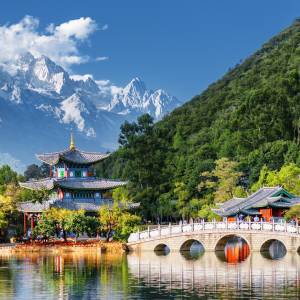 Blick vom Schwarzer-Drachen-Teich in Lijiang auf eine Brücke und Pagode mit dem Jadedrachen-Schneeberg im Hintergrund