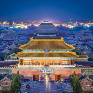 Erleuchtetes Nordtor der Kaiserstadt in Peking vor der nächtlichen Skyline der Stadt.