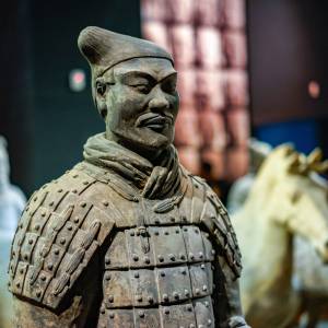 Tonkrieger im Vordergrund mit Pferdestatuen im Hintergrund im Qin Shi Huang Mausoleum Museum​​ in Xian China