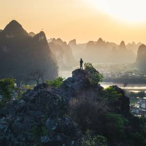 Silhouette bei Sonnuntergang einer Person auf einem Felsen mit dem Hintergurnd des Karstgebirges von Yanghsou China