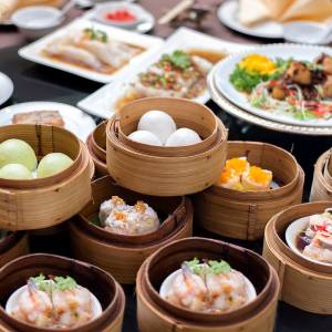 Anordnung verschiedener Dim Sum in diversen Bambuskörben auf einem Tisch in einem chinesischen Restaurant