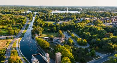 Aerial view of the Trent-Severn Waterway in Peterborough, with canoes on the canal and tree-lined parks all around.
