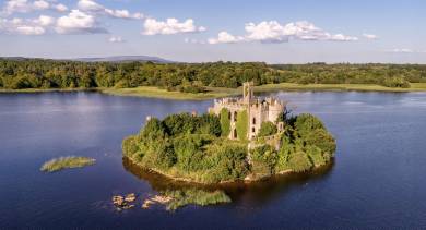 Drone view of the ivy-covered ruins of a castle on a small island in Lough Key.