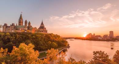 The Rideau Canal locks run through the heart of Ottawa with Parliament Hill and Château Laurier glowing under a soft evening sky.