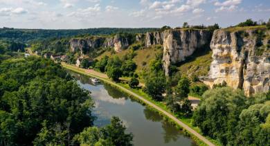 Una barca naviga lungo un fiume sotto spettacolari scogliere calcaree a Merry-sur-Yonne, in Borgogna.