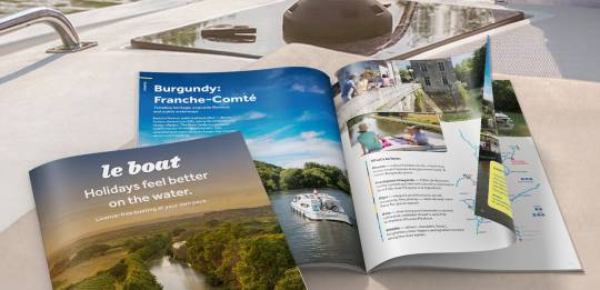 Le Boat holiday brochures displayed on a boat deck, highlighting scenic canal cruising destinations